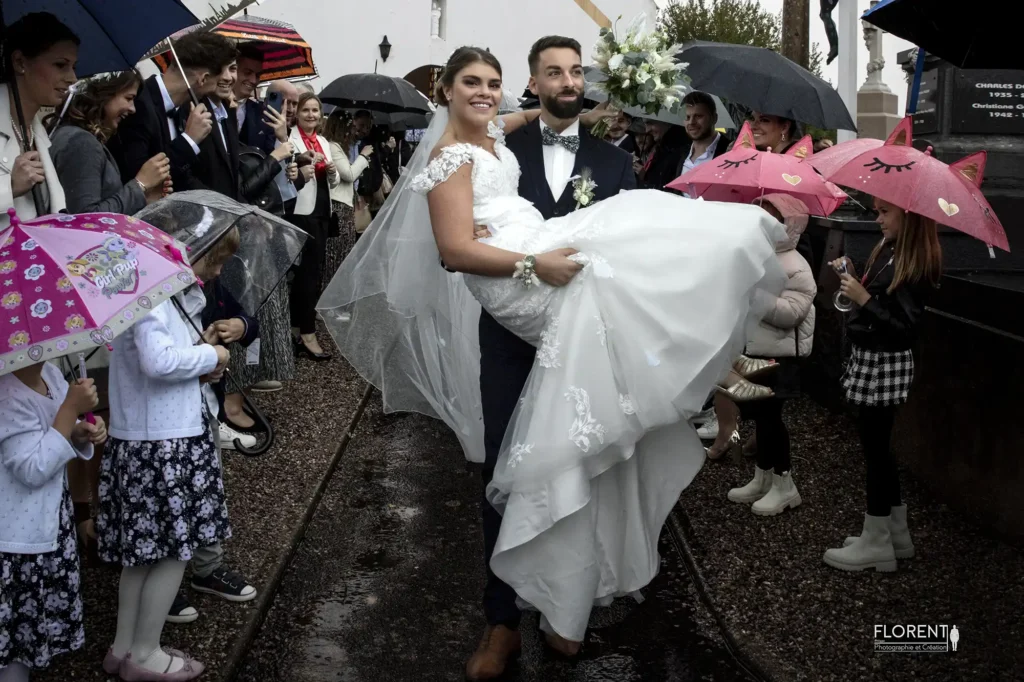 photographe mariage lille marie porte mariee souriante sous la pluie parapluie des temoins florent studio photographe boulogne sur mer lille calais saint omer le touquet paris france bethune