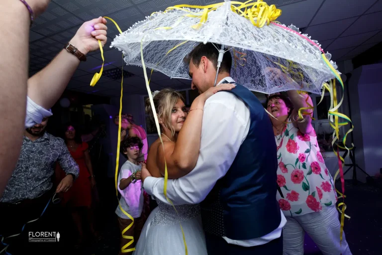 mariage fete maries tendres sous ombrelle et invites cotillons s embrassent florent studio photographe mariage pas de calais nord boulogne sur mer lille paris arras le touquet