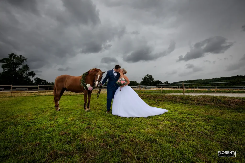 mariage saint omer superbe photo les maries s'embrasse avec leur cheval sous la pluie au milieu du manege studio photographe mariage pas de calais nord boulogne sur mer lille paris arras calais