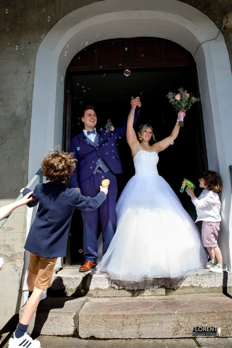 mariage sortie joyeuse eglise selles saint omer epoux levent les bras avec bulles florent studio photographe mariage pas de calais nord boulogne sur mer lille paris arras le touquet
