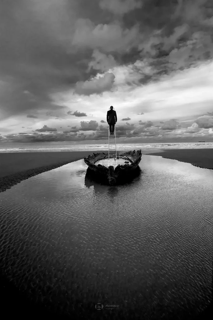 photo art saint omer noir et blanc Homme sommet échelle dans une barque échouée. Boulogne sur mer. Florent philippe photographe lille paris calais