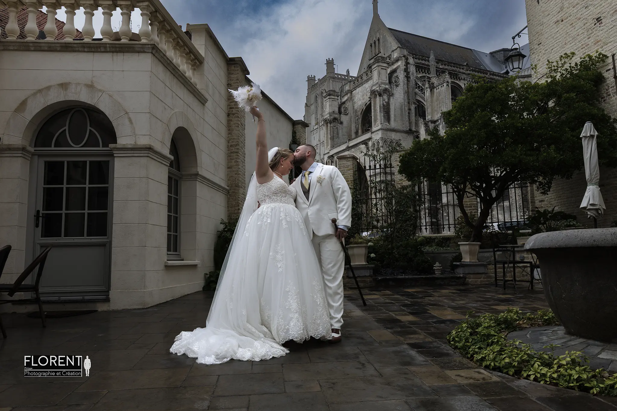 mariage-joyeux-saint-omer-clos-bailli-vue-sur-la-cathedrale-sous-la-pluie-epoux-s-embrasse-la-marie-jette-son-bouquet-florent-studio