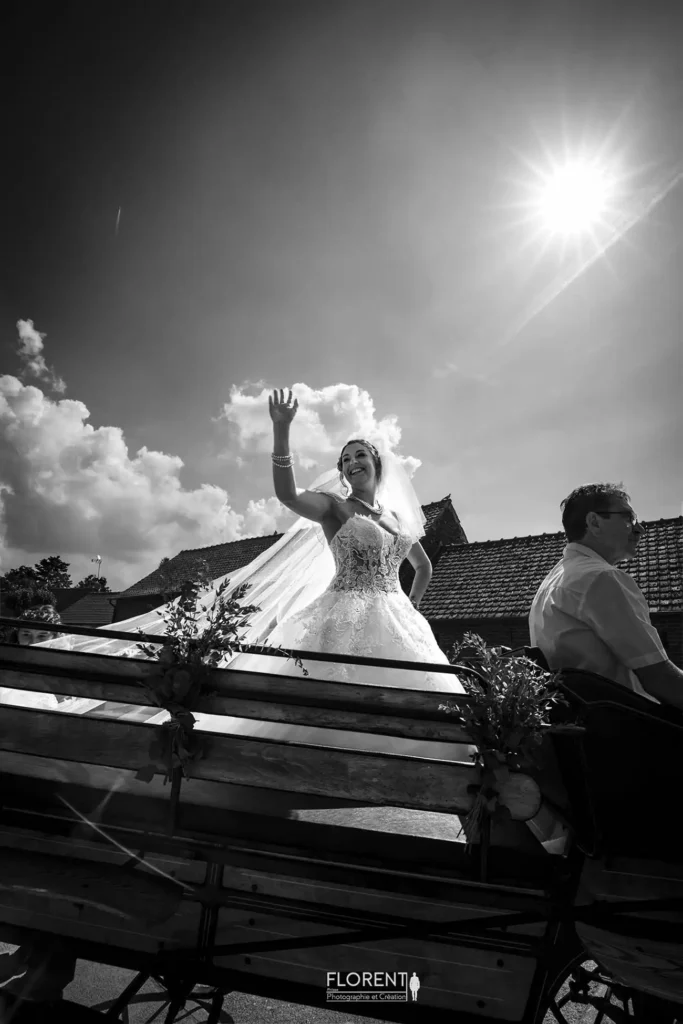photographe-mariage-lille-la-mariee-salut-les-amis-sur-son-carosse-tire-par-des-chevaux-blancs-du-boulonnais-studio-florent-photographe-boulogne-sur-mer-le-touquet-paris-calais-saint-omer.webp